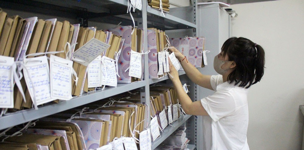 Cán bộ sắp xếp hồ sơ, tài liệu trên kệ trong kho lưu trữ
